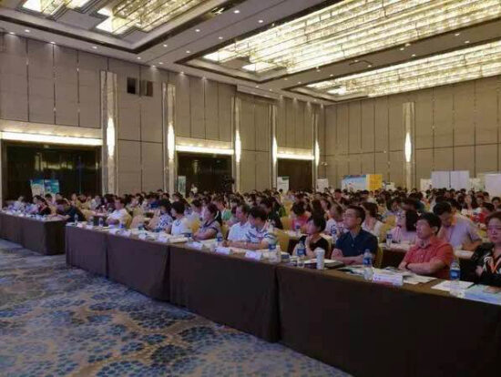 Conference hall audience seated at long tables
