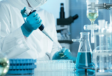 Technician pipetting in a blue-lit laboratory